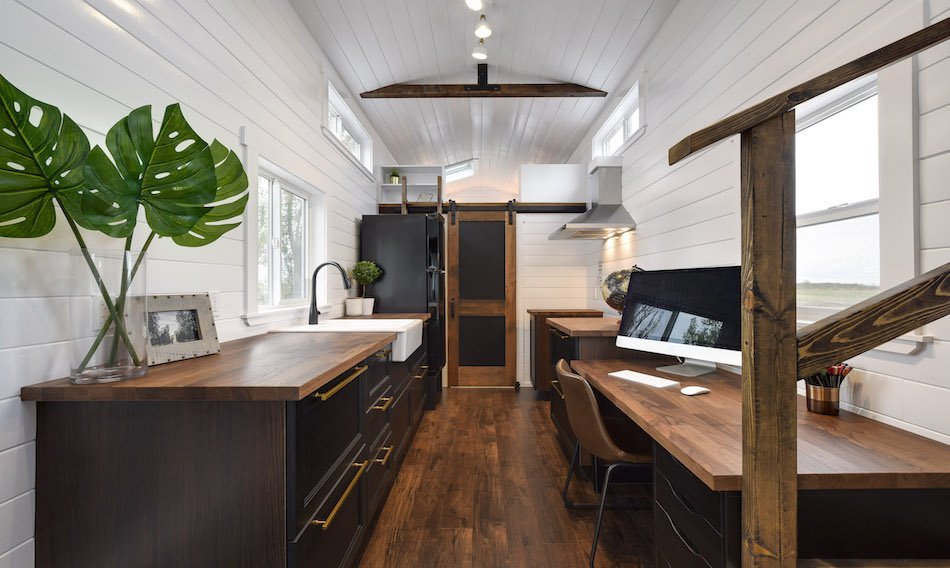 Luxury tiny home interior with dark wood cabinetry and desk nook